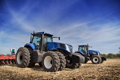 Ferguson & Menzies universal tractor oils promotion featuring two blue tractors in a field on a sunny day 